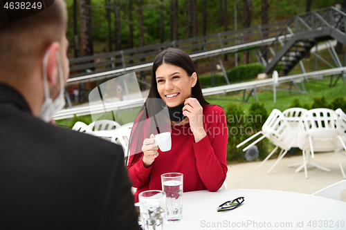 Image of couple with protective medical mask  having coffee break in a re