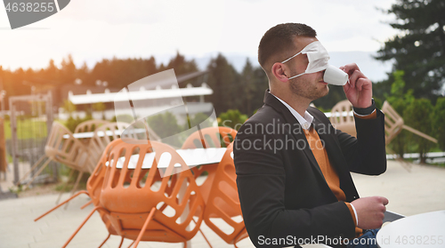 Image of funny man in restaurant drinking coffee wearing face mask