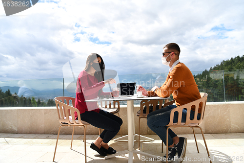 Image of couple with protective medical mask  having coffee break in a re