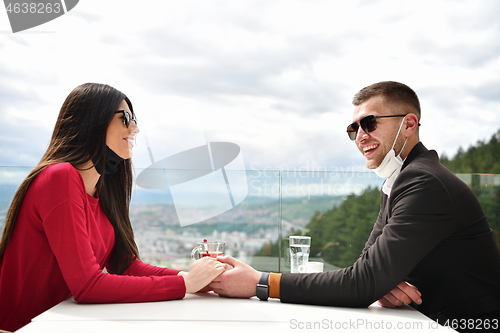 Image of couple with protective medical mask  having coffee break in a re