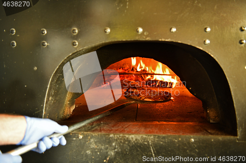 Image of chef  with protective coronavirus face mask preparing pizza