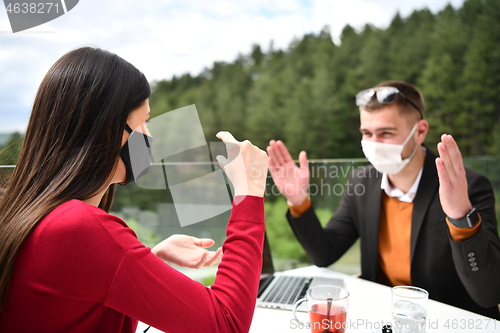 Image of couple with protective medical mask  having coffee break in a re