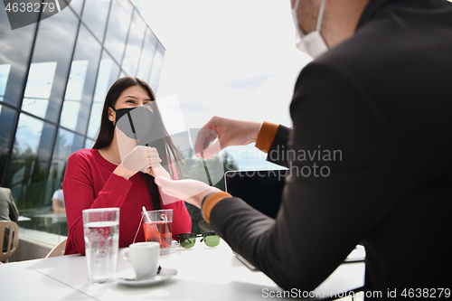 Image of couple with protective medical mask  having coffee break in a re