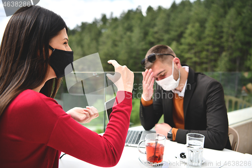 Image of couple with protective medical mask  having coffee break in a re
