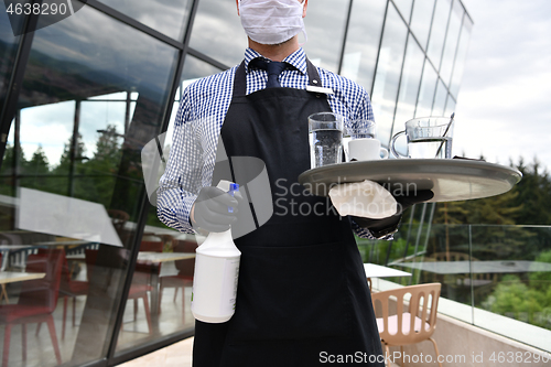 Image of Waiter cleaning the table with Disinfectant Spray in a restauran