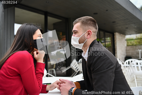 Image of couple with protective medical mask  having coffee break in a re