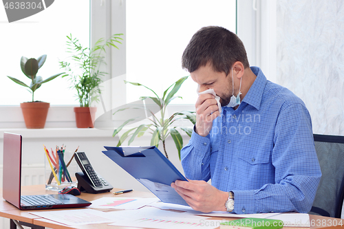 Image of diseased workaholic in the office works with documents and swipes in a napkin