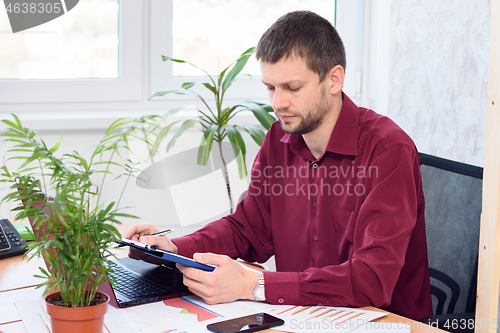 Image of office employee works on a tablet in a light office