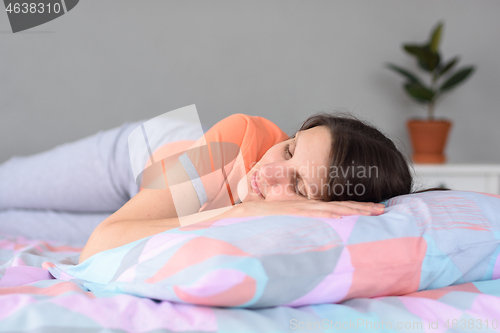 Image of Girl in pajamas lies in bed during the day and tries to sleep