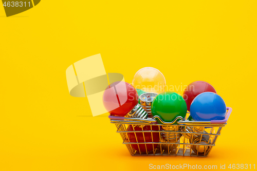 Image of multi-colored light bulbs in a metal basket on a yellow background