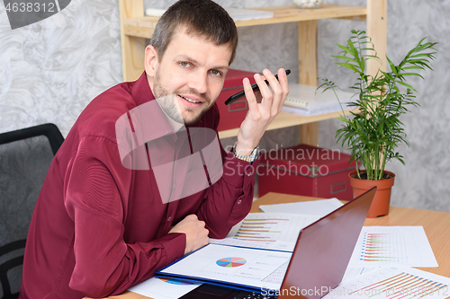 Image of Man in the office listens to voicemail on mobile phone