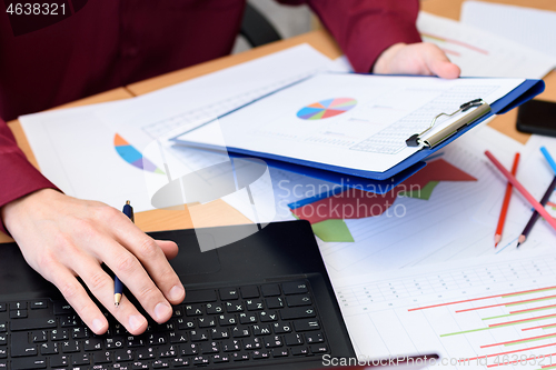 Image of close-up of desktop with documents, laptop, graphs, tables