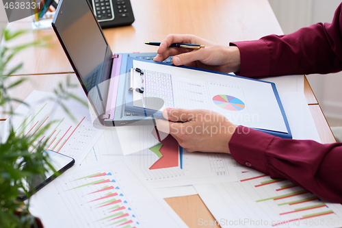 Image of close-up of the office worker holding a tablet with documents and graphs