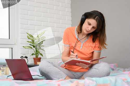 Image of Girl student at home writes online lecture materials in a notebook