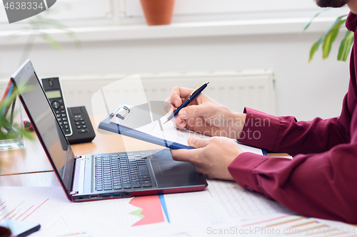 Image of close-up of hands of men making notes in a notebook against the background of the desktop