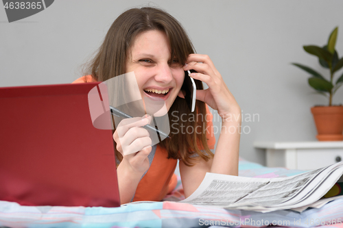 Image of Girl laughs a lot while talking with the employer on the phone and looking for work
