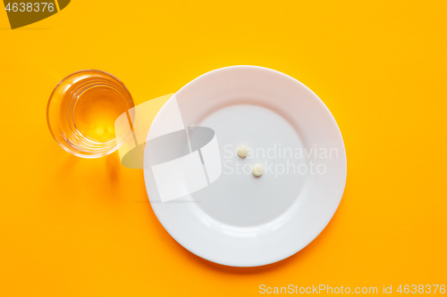 Image of On the plate are two tablets, next is a glass of water