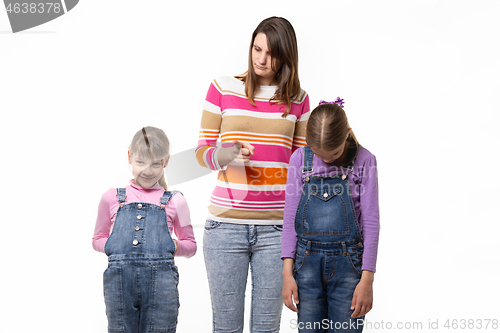 Image of Mom scolds children, one girl smiles another stands wilted