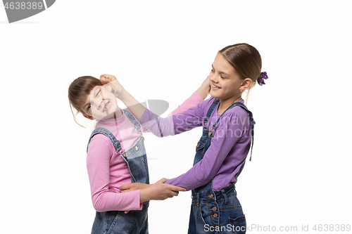 Image of The eldest girl drags the younger one by the ear, isolated