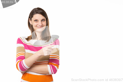 Image of Girl with a charming smile points a finger to an empty place, white background
