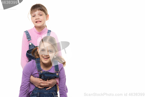 Image of Girl supports another girl by the armpits and cheerfully looks into the frame