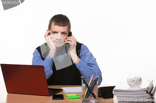 Image of tired employee talking on the phone in an office setting