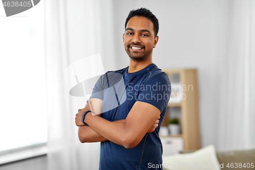 Image of smiling indian man with fitness tracker at home