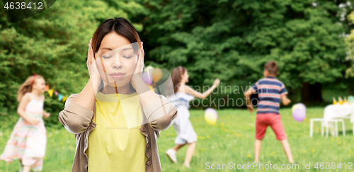 Image of asian woman closing ears over kids party at park