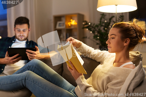 Image of couple with tablet computer and book at home