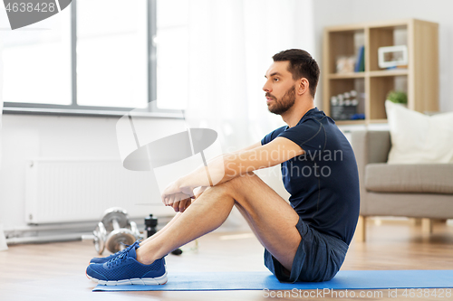 Image of man resting on exercise mat at home