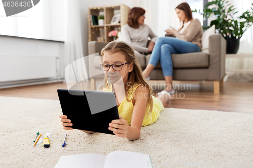 Image of girl with tablet computer lying on floor at home