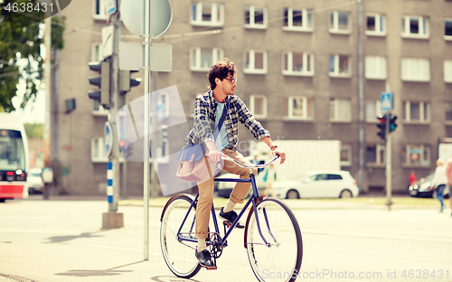 Image of young hipster man with bag riding fixed gear bike