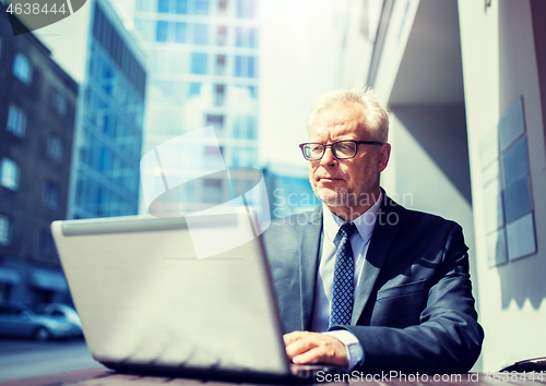 Image of senior businessman with laptop at city street cafe