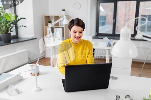 Image of happy businesswoman with laptop working at office