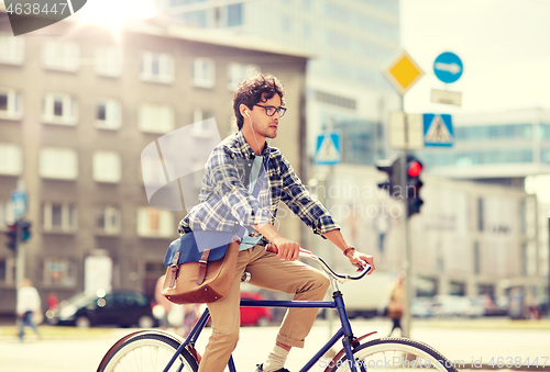 Image of young hipster man with bag riding fixed gear bike