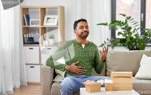 Image of pleased indian man eating takeaway food at home