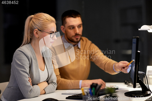 Image of business team with computer working late at office