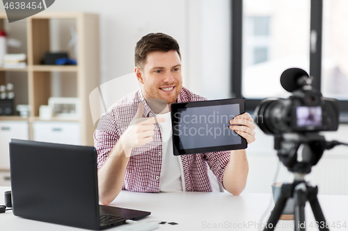 Image of male blogger with tablet pc videoblogging at home