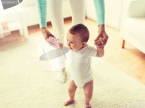 Image of happy baby learning to walk with mother help