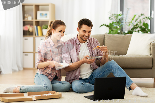 Image of happy couple with laptop eating pizza at home