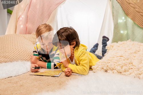 Image of boys with magnifier and map in kids tent at home