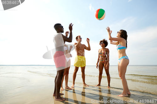 Image of happy friends playing ball on summer beach