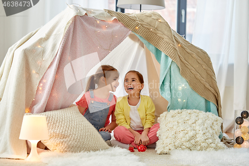 Image of little girl playing tea party in kids tent at home