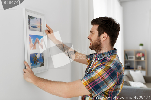 Image of man hanging picture in frame to wall at home