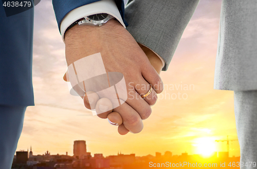 Image of close up of male gay hands with wedding rings on