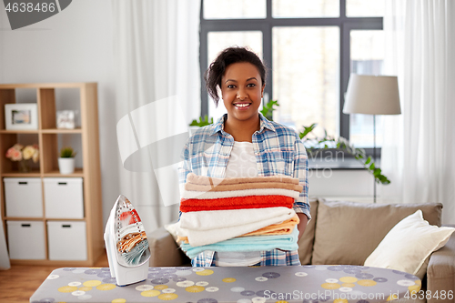 Image of african american woman with ironed linen at home