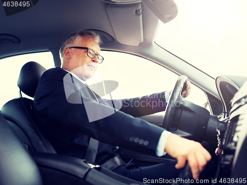 Image of happy senior businessman driving car