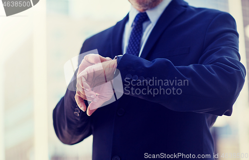 Image of senior businessman with wristwatch on city street