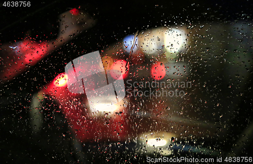 Image of Lights of night city through the glass of the car with raindrops