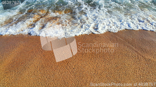 Image of Sea wave with white foam on the sandy beach